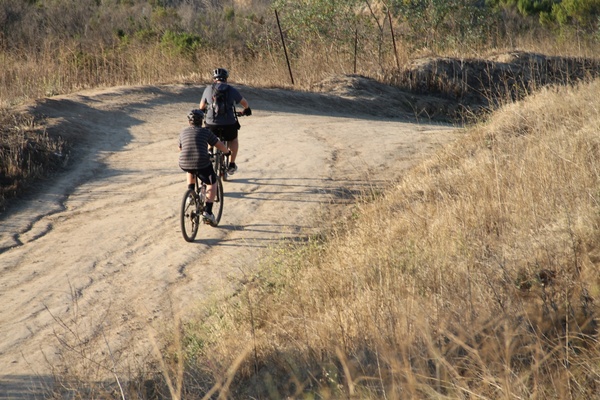 2 bicyclists riding on dirt trail