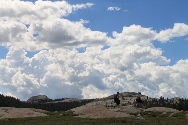 2 women hiking over rocks under clouds