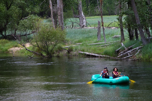 2 women paddling in a raft down a river
