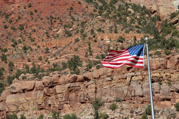 american flag waving in front of rocky cliffs