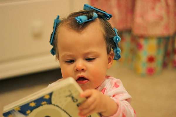 baby girl reading with hair in curlers