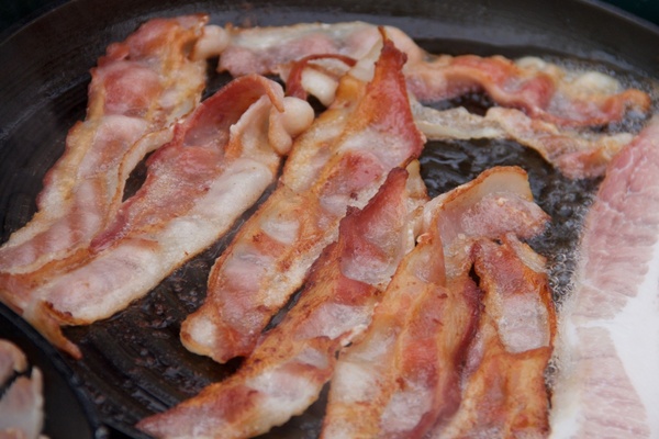 bacon strips cooking in frying pan