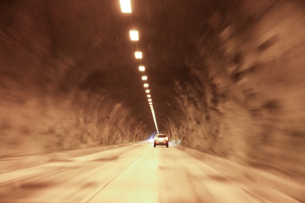 car drive down tunnel with overhead lights
