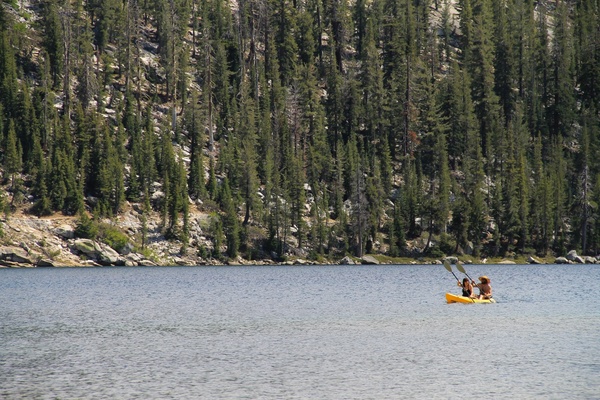 couple kayaking on a lake by forest