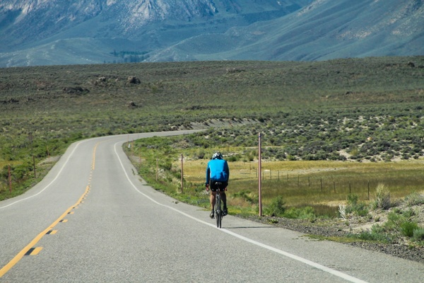 cyclist on road towards mountains