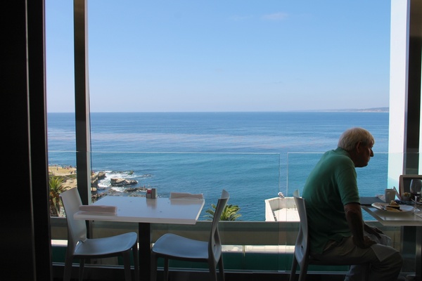 elderly man sitting in restaurant by ocean