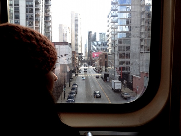 girl in beanie hat peering at downtown city on train