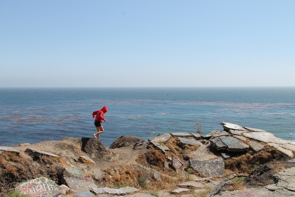 girl walking across rocks by ocean 