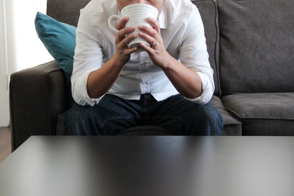 man on couch drinking from mug