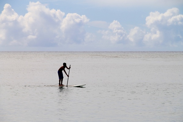 man paddling on surfboard in ocean