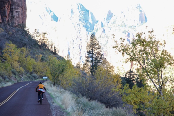 man riding on bicycle alongside mountains 