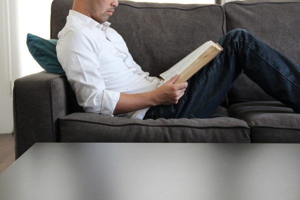 man sitting on couch reading bible