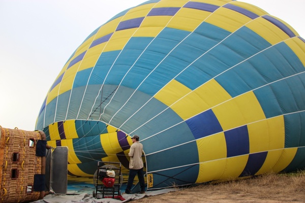 man standing by inflating hot air ballon 