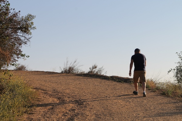 man walking up a dirt trail