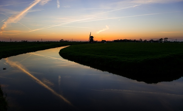 mill at sunset with a river in front