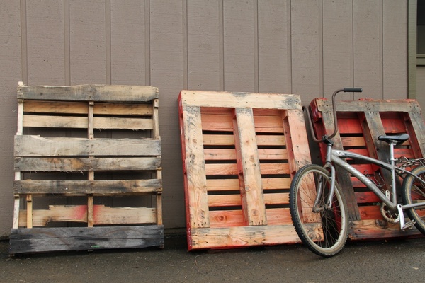 old bicycle leaning against wood pallets 