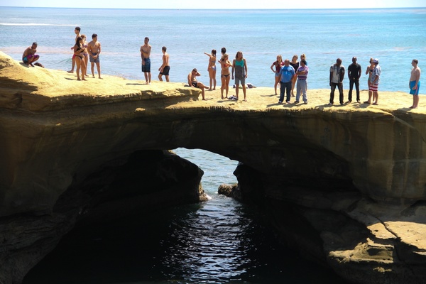 people standing on rock ledge over ocean