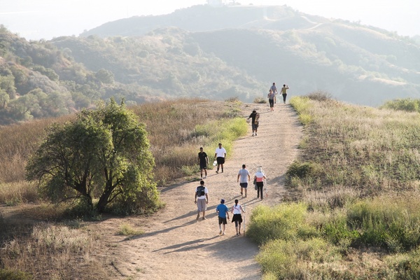people walking on dry dirt trail over hill