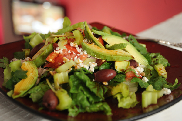 perfectly delightful summer salad avocado celery romaine lettuce olives feta cheese almonds tomato tamari sauce olive oil served on a square maroon zen plate silver fork second floor loft seattle washington usa 