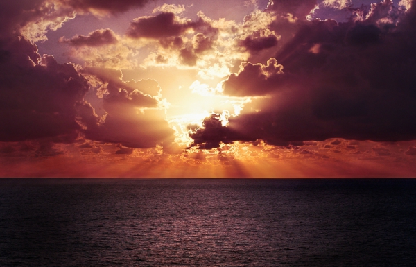 sun rays shining through clouds during calm ocean sunset