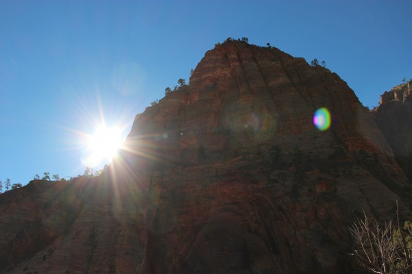 sun shining next to rock mountain