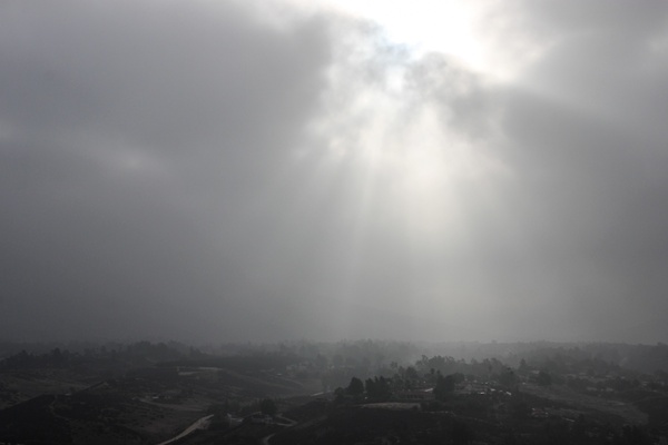 sunlight shining through thick clouds over hazy town