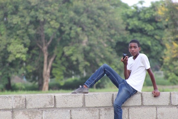 teen boy sitting on brick wall with camera