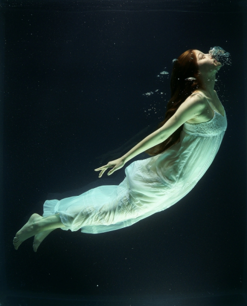 woman diving under water with white dress