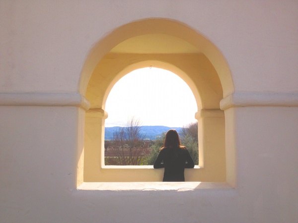 woman looking out arch window 