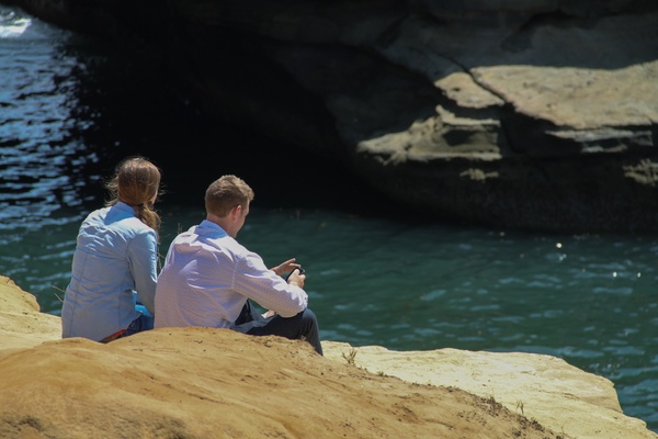 young couple sitting on rocks by water