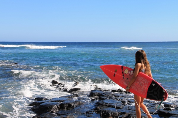 young girl holding surfboard at ocean