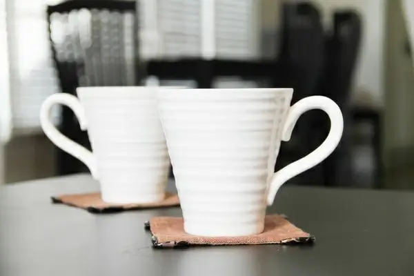 2 white coffee mugs on coasters 