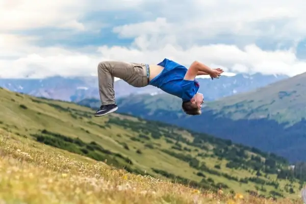 excited man performing acrobatics on hill