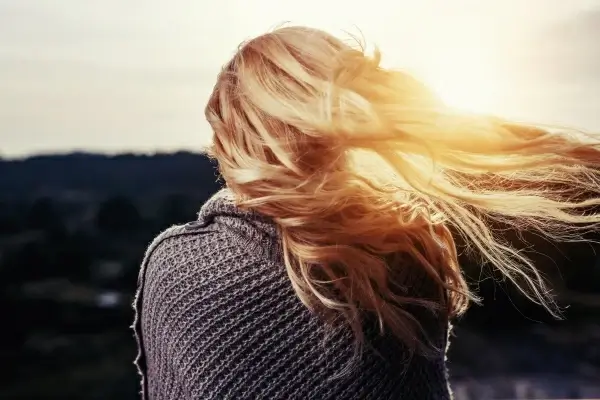 attractive woman enjoying sunlight with hair flying in wind