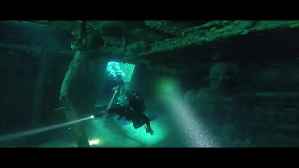 divers discovering wrecked ship in deep sea