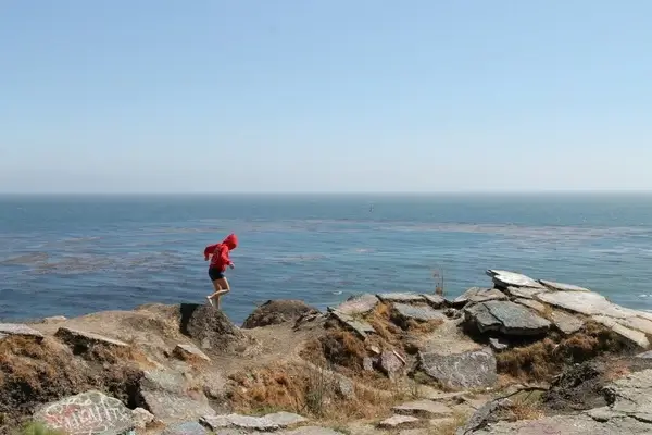 girl walking across rocks by ocean