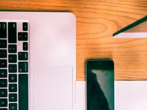 laptop and phone on wooden desk 