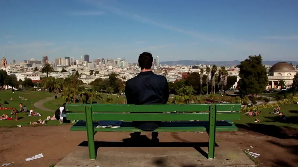 lonely man sitting on bench watching cityscape