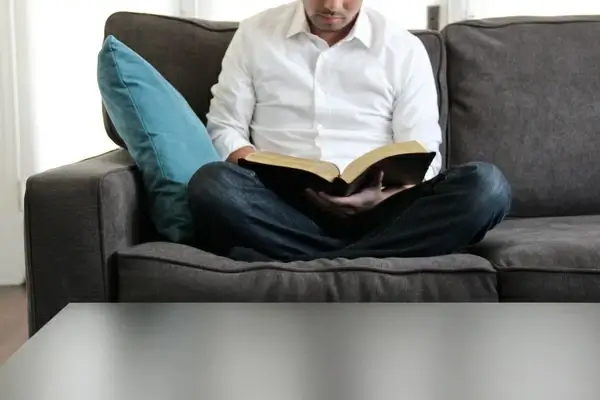 man on couch reading bible
