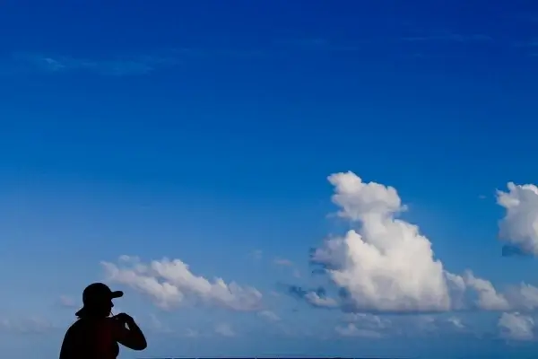 silhouette of woman on blue sky with clouds