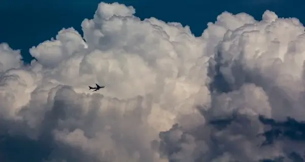 airplane flying in big white cloud