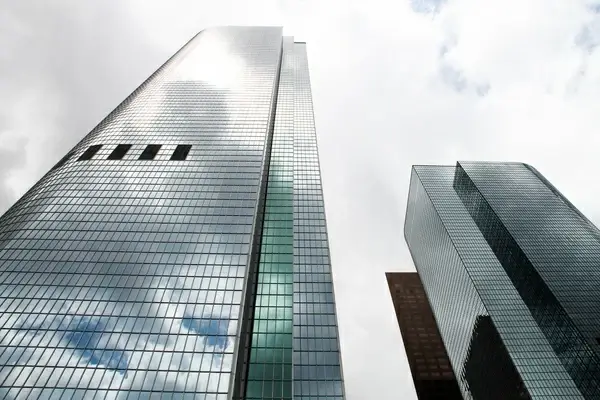 tall glass skyscraper reflecting clouds