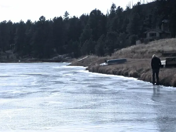 woman walking along edge of frozen lake