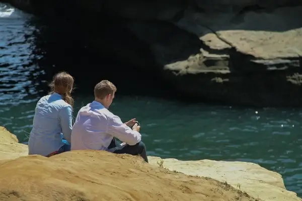 young couple sitting on rocks by water