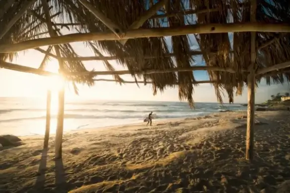 man with surfboard on deserted beach