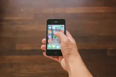 hand holding iphone 4 selecting facebook app
