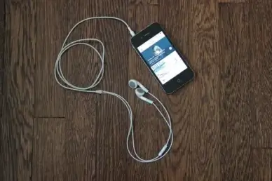 iphone 4 with earbuds on wooden table