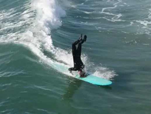 longboard surfer does a headstand