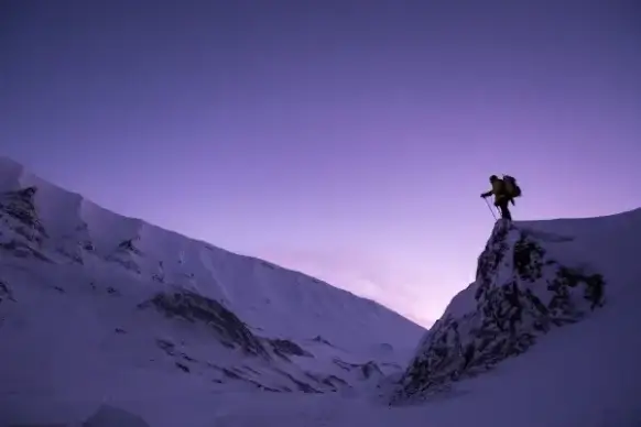 mountaineer standing on top of a rock