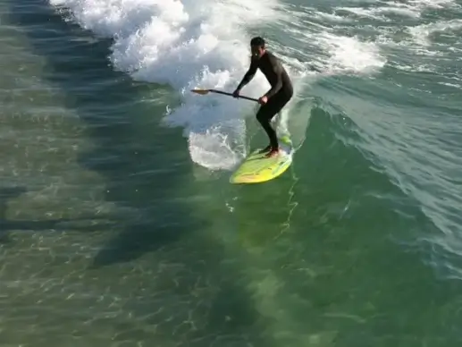 paddleboarder catches a glass wave